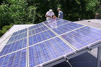 Workers installing solar panels on a roof near Poughkeepsie, N.Y.