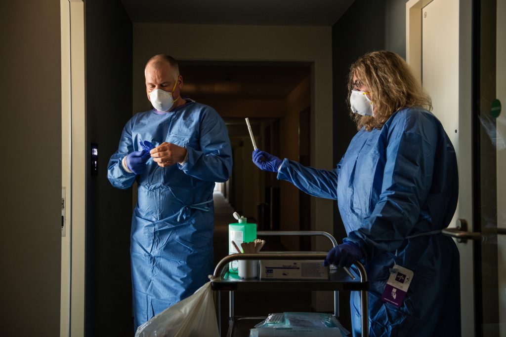 Tim Heitland puts gloves on before entering the room of a MOSAiC participant to take a smear for COVID-19 test. Credit: Esther Horvath/Alfred-Wegener-Institut