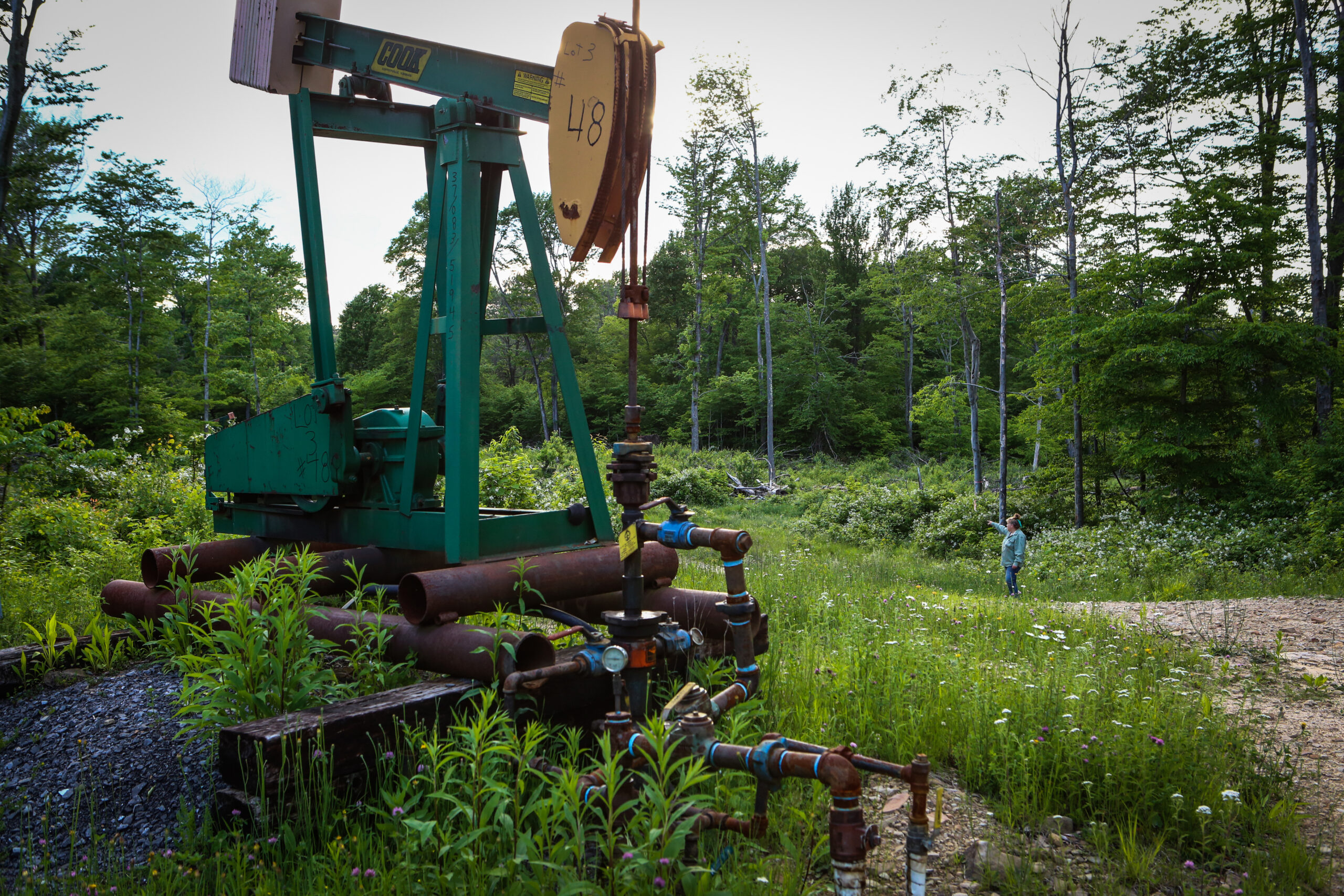 Laurie Barr, co-founder of Save Our Steams Pennsylvania, searches abandoned oil wells for pollutants as an old pumpjack stands in the Allegeny National Forest near Marienville, Pennsylvania, on Monday, June 6, 2016. Credit: Chris Goodney/Bloomberg via Getty Images