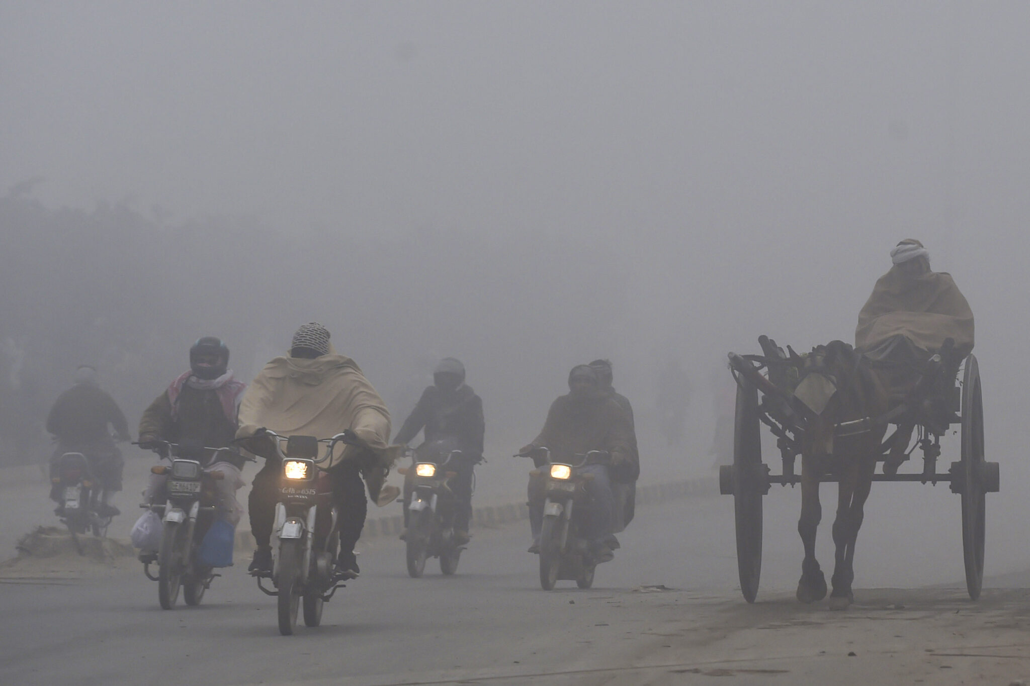 Commuters make their way along a street amid smoggy conditions early in the morning in Lahore, Pakistan on Dec. 17, 2021. Credit: Arif Ali/AFP via Getty Images
