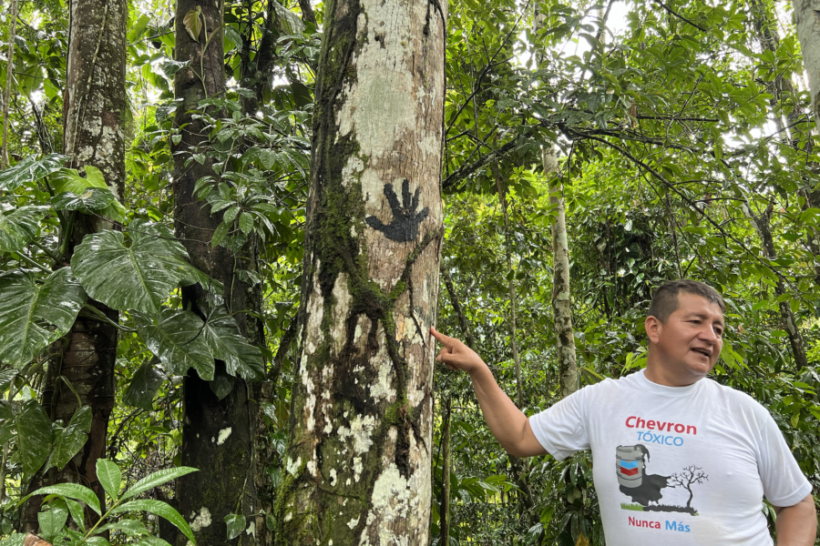 Donald Moncayo, president of The Union of People Affected by Texaco, stands next to an oil stained handprint at a former Texaco drilling site in the province of Sucumbíos, Ecuador on Aug. 11, 2022. Credit: Katie Surma/Inside Climate News
