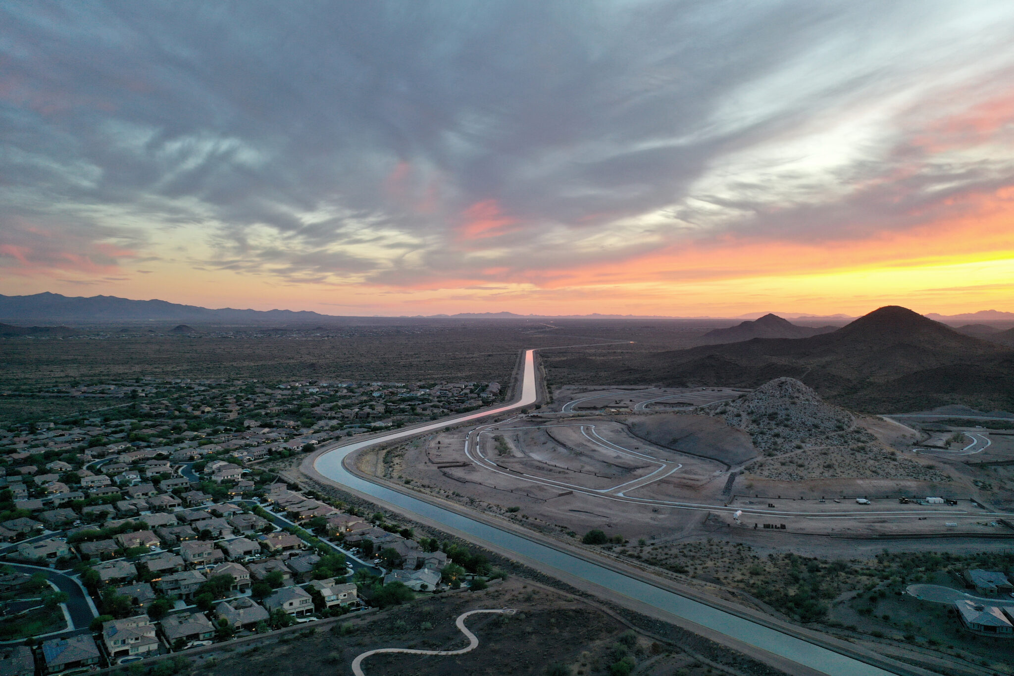 The Central Arizona Project canal runs past homes and new home construction, center right, in the Phoenix suburbs on June 8, 2023 in Peoria, Arizona. The project carries diverted Colorado River water through a 336-mile long system to help serve 80 percent of the population of Arizona. Credit: Mario Tama/Getty Images