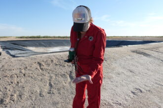 Oil and gas lawyer Sarah Stogner picks up a salt crystal left over from produced water that spewed from a geyser at an orphaned well. Credit: Martha Pskowski/Inside Climate News