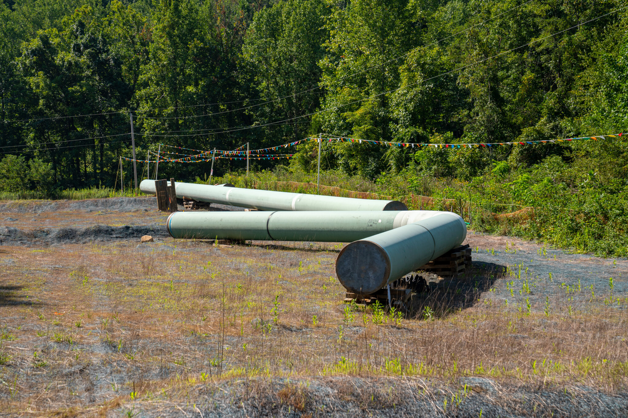 Sections of steel pipe of the Mountain Valley Pipeline sit on wooden blocks in August 2022 near wetland areas in Callaway, Virginia. The state's General Assembly has diminished the power of residents to engage in the decision-making process for permitting and siting such projects as the Mountain Valley Pipeline under the state Department of Environmental Quality, a key environmental justice provision under Virginia law. Credit: Robert Nickelsberg/Getty Images