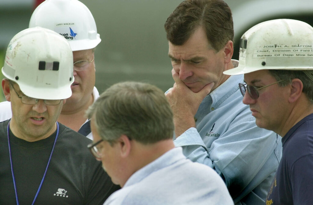 In July 2002, then-Pennsylvania Gov. Mark Schweiker, second from right, listens to a progress report on rescue efforts at Quecreek Mine in Somerset, Pennsylvania. At right is Joseph A. Braffoni, of the Bureau of Deep Mine Safety, second from left is Larry Winckler, center is David Hess, Pennsylvania secretary of the Department of Environmental Protection and at left is Jeffery Stanchek a mine rescue instructor for the DEP. They were coordinating efforts to reach nine miners trapped for three days. Credit: Gene J. Puskar/ AFP via Getty Images.