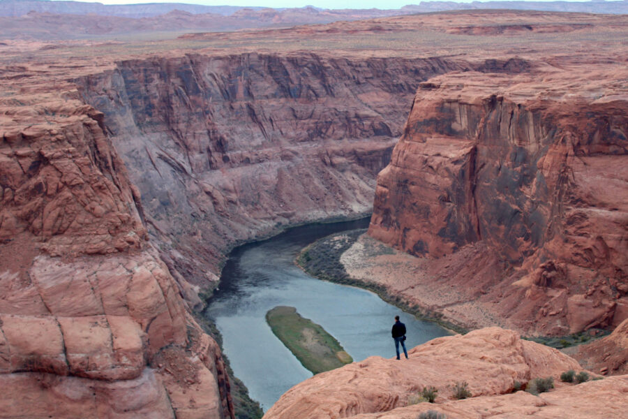 A man looks out over the Colorado River near Page, Ariz. on Nov. 2, 2022. The seven states that manage the river are divided about how to account for the impacts of climate change in new plans about sharing its water. Credit: Alex Hager/KUNC