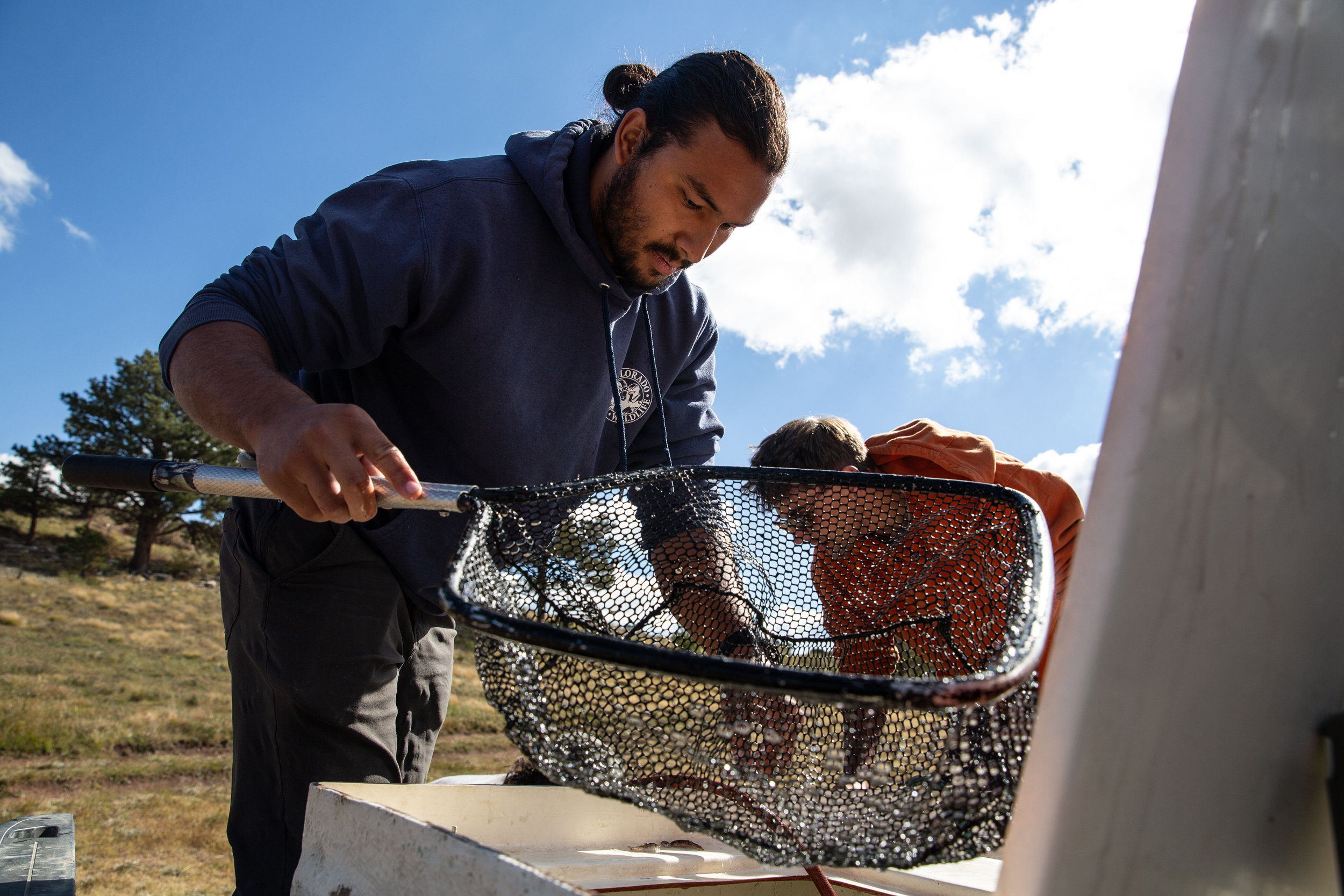 Jack Bonner and Dakotah Pinkus, technicians for Colorado Parks and Wildlife, transfer trout fry that will be dropped into a lake in the Sangre de Cristo Mountains during an assisted migration in 2022. The Rio Grande cutthroat trout were transferred to a watershed cooler than its’ typical range to account for climate change. Credit: Luna Anna Archey/High Country News