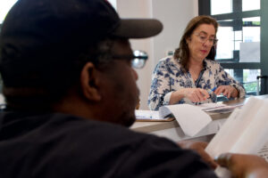 Laurel Peltier, an energy justice advocate who volunteers at the local nonprofit Cares, goes over utility bills to determine if her client Henry Burlock was overcharged by a private energy company. Credit: Aman Azhar/Inside Climate News