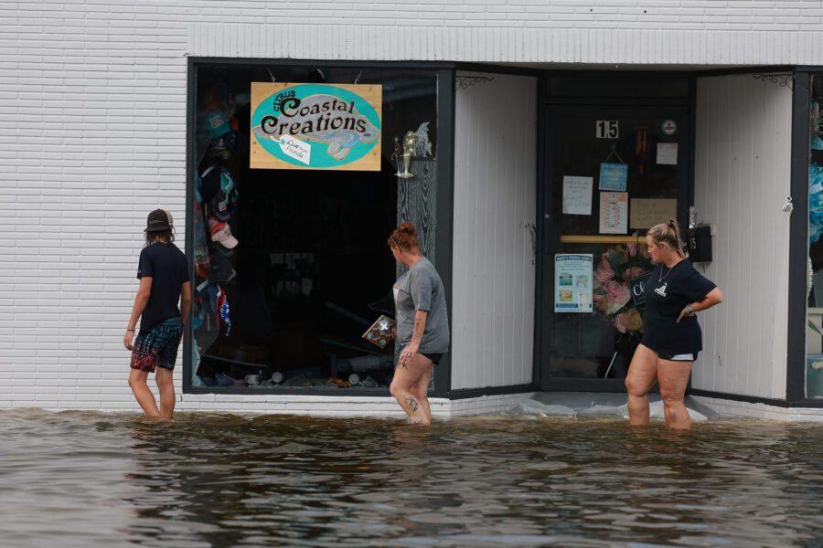 People walk through flood waters past a store with a broken window on Aug. 30, 2023 after Hurricane Idalia hit Crystal River, Fla. Credit: Joe Raedle/Getty Images