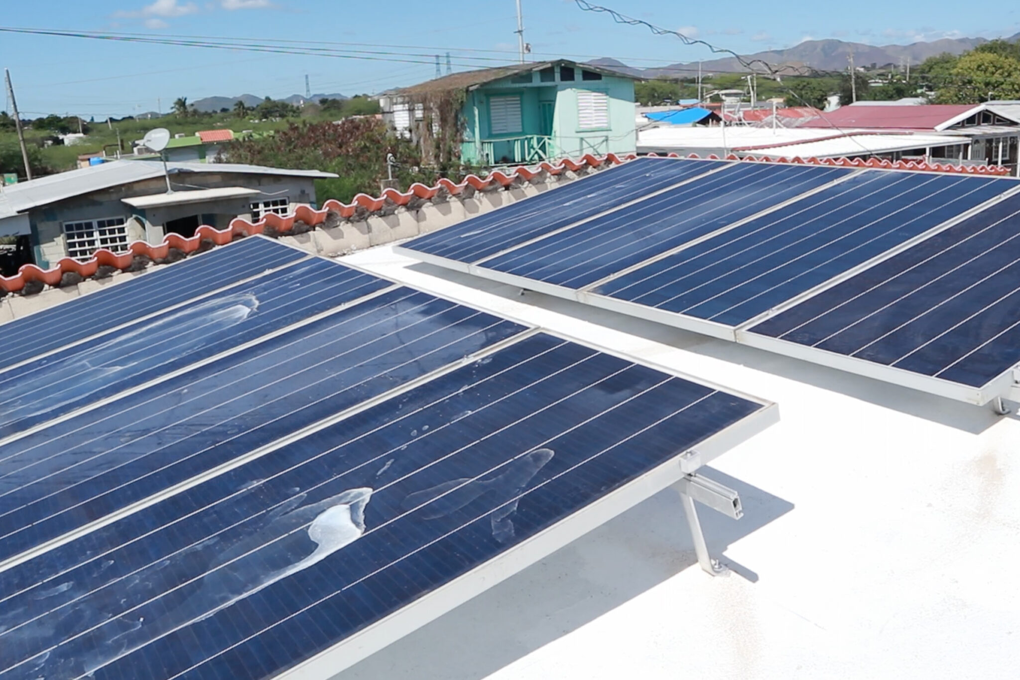 Electricians from Coquí Solar install two racks of solar panels onto a rooftop in Salinas, Puerto Rico. Each panel produces 315 watts of power that can be stored in solar batteries for use during an electrical blackout. Credit: Esther Frances/Medill News Service