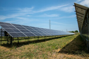 A high tension electrical power pole is seen in the background of a solar array in Blaine, Minn. Credit: Michael Siluk/UCG/Universal Images Group via Getty Images