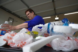 Brandy Deason, a climate justice coordinator for Air Alliance Houston concerned about pollution from chemical recycling of plastic waste, prepares a bag of plastic waste packed with an electronic tracker to see if it’s being recycled. Credit: Dwaine Scott/CBS News