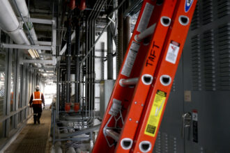 A worker makes his way down a corridor on the third floor of One Wilshire, a high-rise office building that has been almost entirely converted into a data center for AI, in downtown Los Angeles on Sept. 10. Credit: Genaro Molina/Los Angeles Times via Getty Images