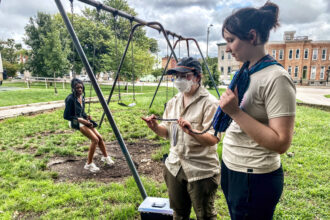 Sam Votzke (left) demonstrates how she performs research work with her field assistant, Olivia Bond. Credit: Aman Azhar/Inside Climate News