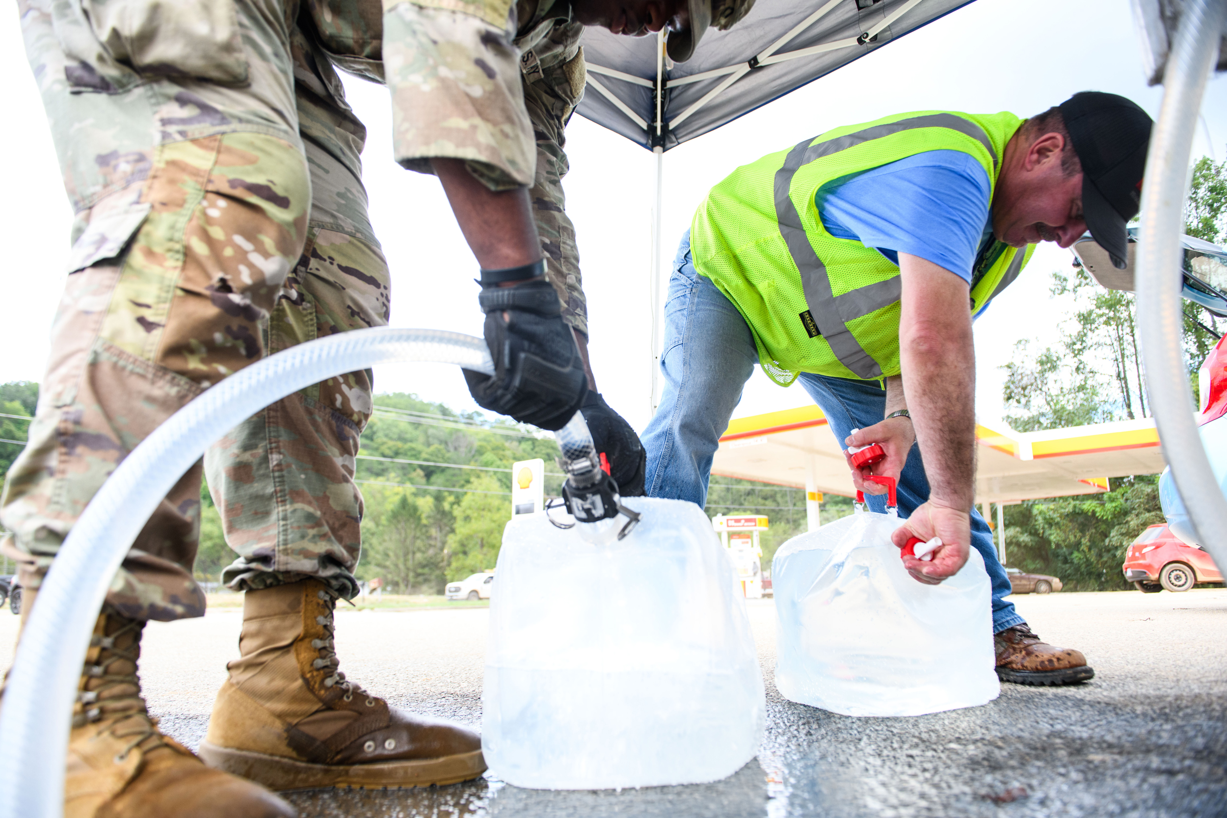An Army National Guard member assists a resident with potable water in the aftermath of Hurricane Helene on Sept. 29 in Old Fort, N.C. Credit: Melissa Sue Gerrits/Getty Images