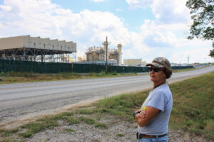 Cheryl Shadden stands at the edge of her property across the street from the Wolf Hollow II power plant, which provides electricity for the Marathon Digital Bitcoin mining facility, in Granbury, Texas. Credit: Keaton Peters/Inside Climate News