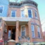 Marisol Genao is smiling in her doorway of a brick end-unit rowhouse
