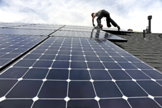 An installer with Namaste Solar secures panels for a photovoltaic solar array system on the roof of a house in Aurora, Colo. Credit: Andy Cross/The Denver Post via Getty Images