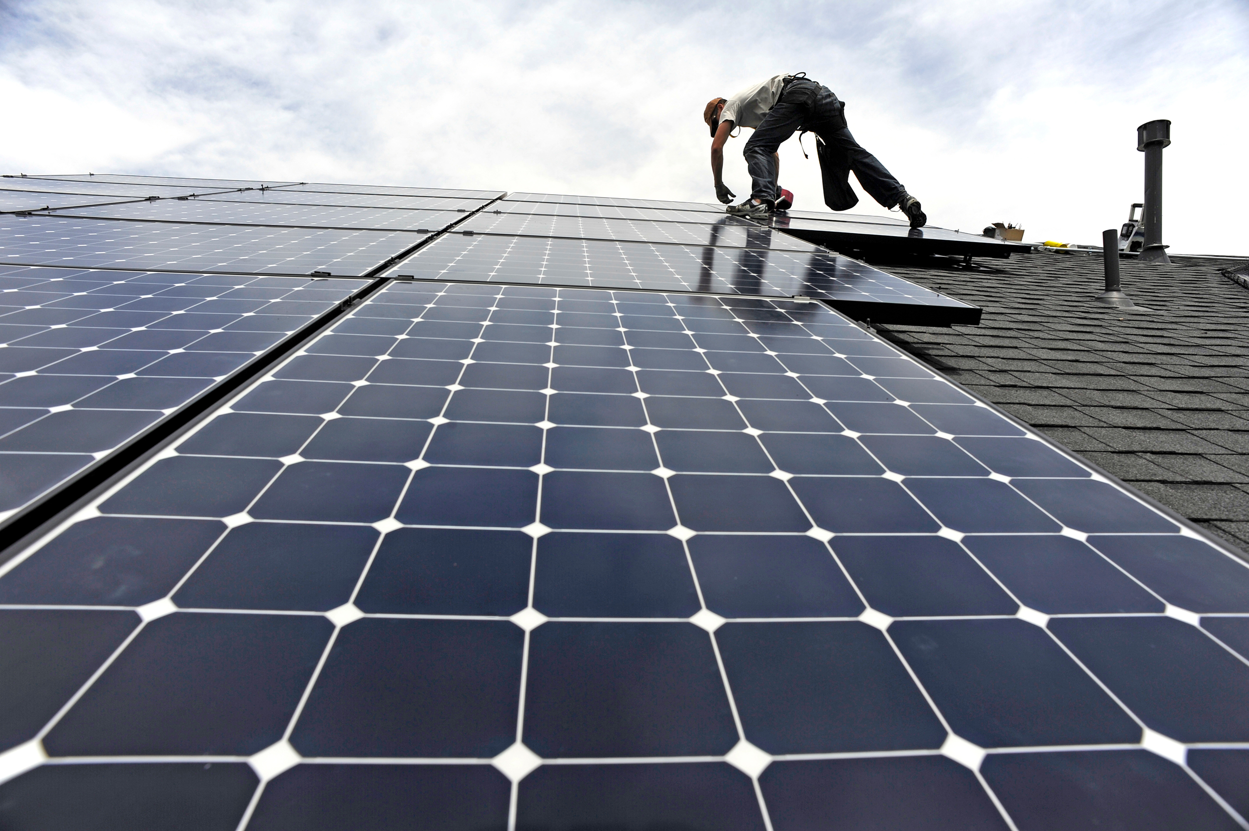 An installer with Namaste Solar secures panels for a photovoltaic solar array system on the roof of a house in Aurora, Colo. Credit: Andy Cross/The Denver Post via Getty Images