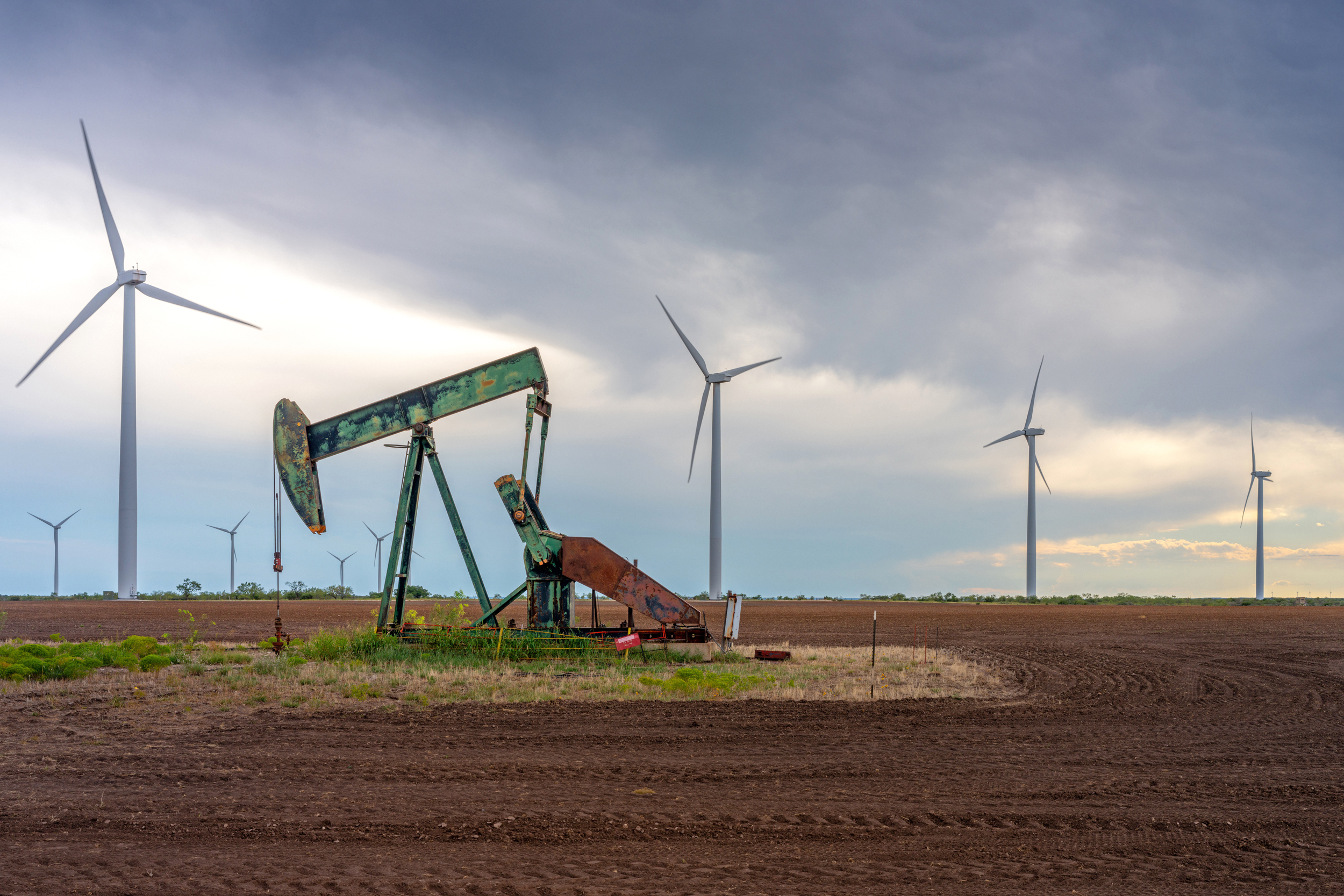 An oil pumpjack is seen near a field of wind turbines in Nolan, Texas. One of the new grants will support a clean energy reporter in Texas, making ICN’s Texas bureau its largest. Credit: Brandon Bell/Getty Images