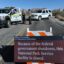 Rangers beside vehicles are in the background. In the foreground, a sign reads: "Because of the federal government shutdown, this National Park Service facility is closed."