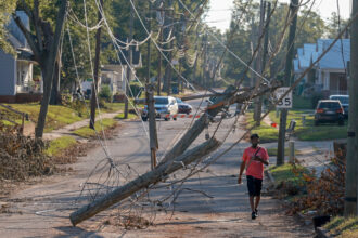 A person walks past downed power lines as South Carolina residents deal with the aftermath of Hurricane Helene on Oct. 5 in Greenwood, S.C. Credit: Joe Raedle/Getty Images