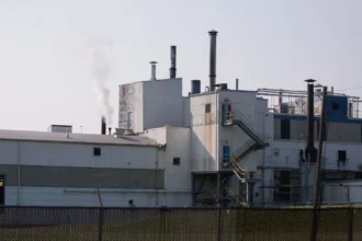 The Goodyear plant is pictured close up, with a white plume coming from a small exterior pipe