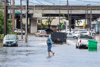 A pedestrian walks across a flooded street in Honolulu on Dec. 7, 2021, the morning after a powerful tropical storm known as a Kona Low hit the Hawaii islands. Credit: Eugene Tanner/AFP via Getty Images