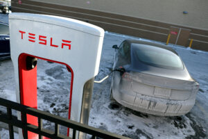 A Tesla charges in a salt and ice covered parking lot in Chicago on Jan. 17, 2024. Credit: Kevin Dietsch/Getty Images