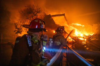 Firefighters fight flames from the Palisades Fire burning the Theatre Palisades during a powerful windstorm on Jan. 8 in Los Angeles. The fast-moving wildfire is threatening homes in the coastal Pacific Palisades neighborhood amid intense Santa Ana winds and dry conditions in Southern California. Credit: Apu Gomes/Getty Images