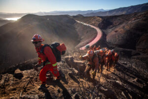 Incarcerated firefighters from the Growlersburg crew hike up a mountain to control the Hughes Fire in Los Angeles County on Jan. 23. Credit: Apu Gomes/AFP via Getty Images