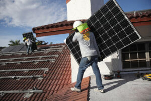 Workers install solar panels on the roof of a home in Palmetto Bay, Fla. Credit: Joe Raedle/Getty Images