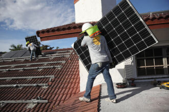 Workers install solar panels on the roof of a home in Palmetto Bay, Fla. Credit: Joe Raedle/Getty Images