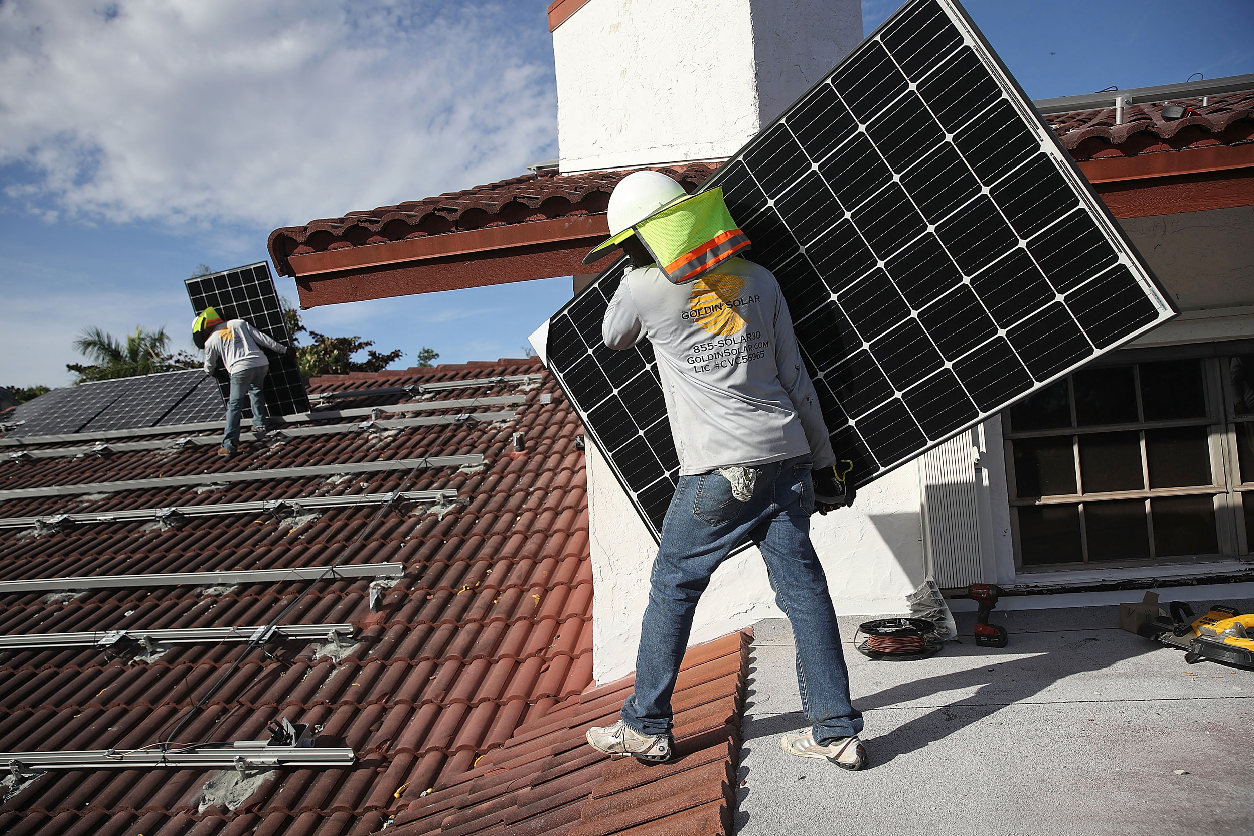Workers install solar panels on the roof of a home in Palmetto Bay, Fla. Credit: Joe Raedle/Getty Images