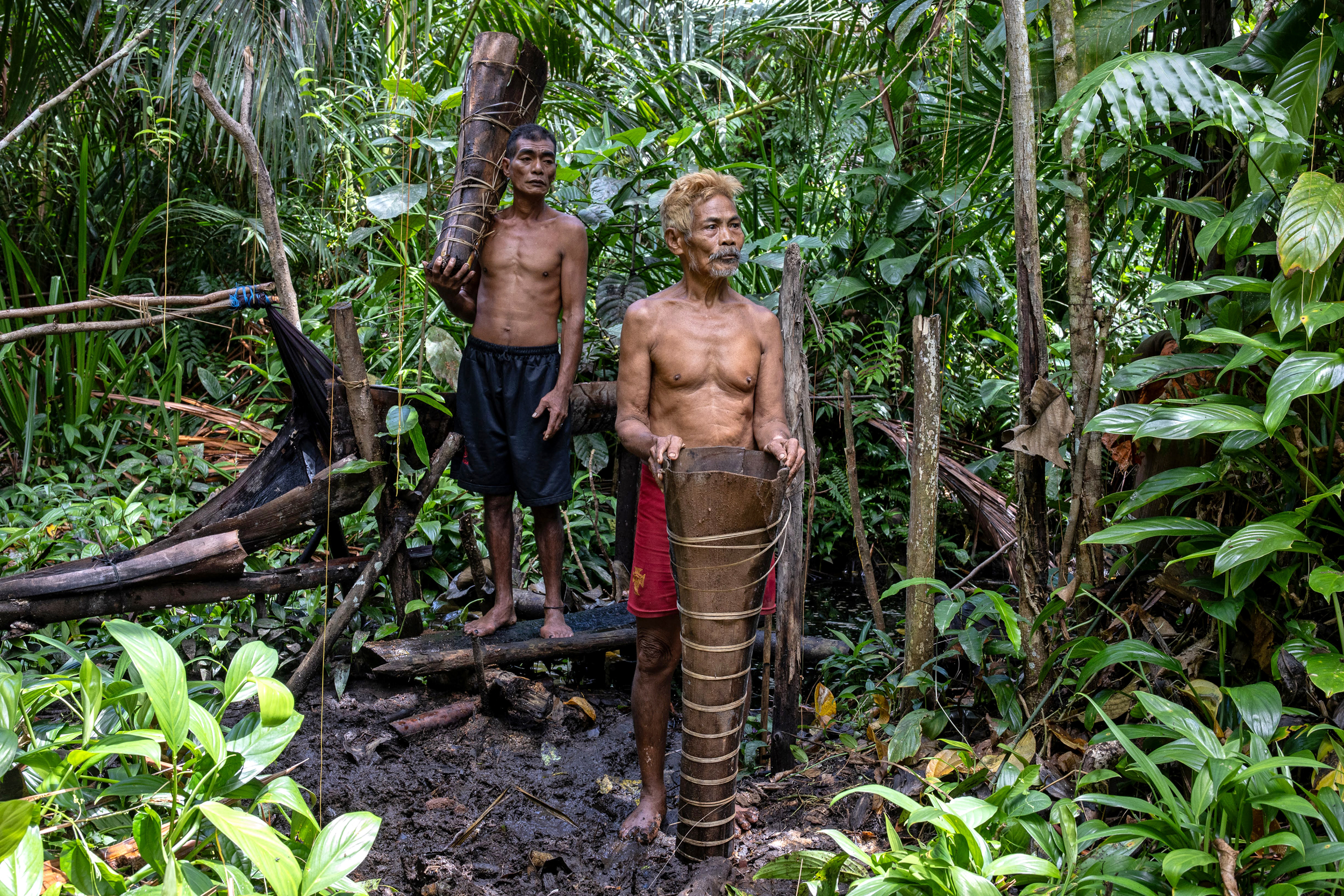 Etus Hurata (left) and Tatoyo Penes take a break from processing sago palm trees to pose for a photo.