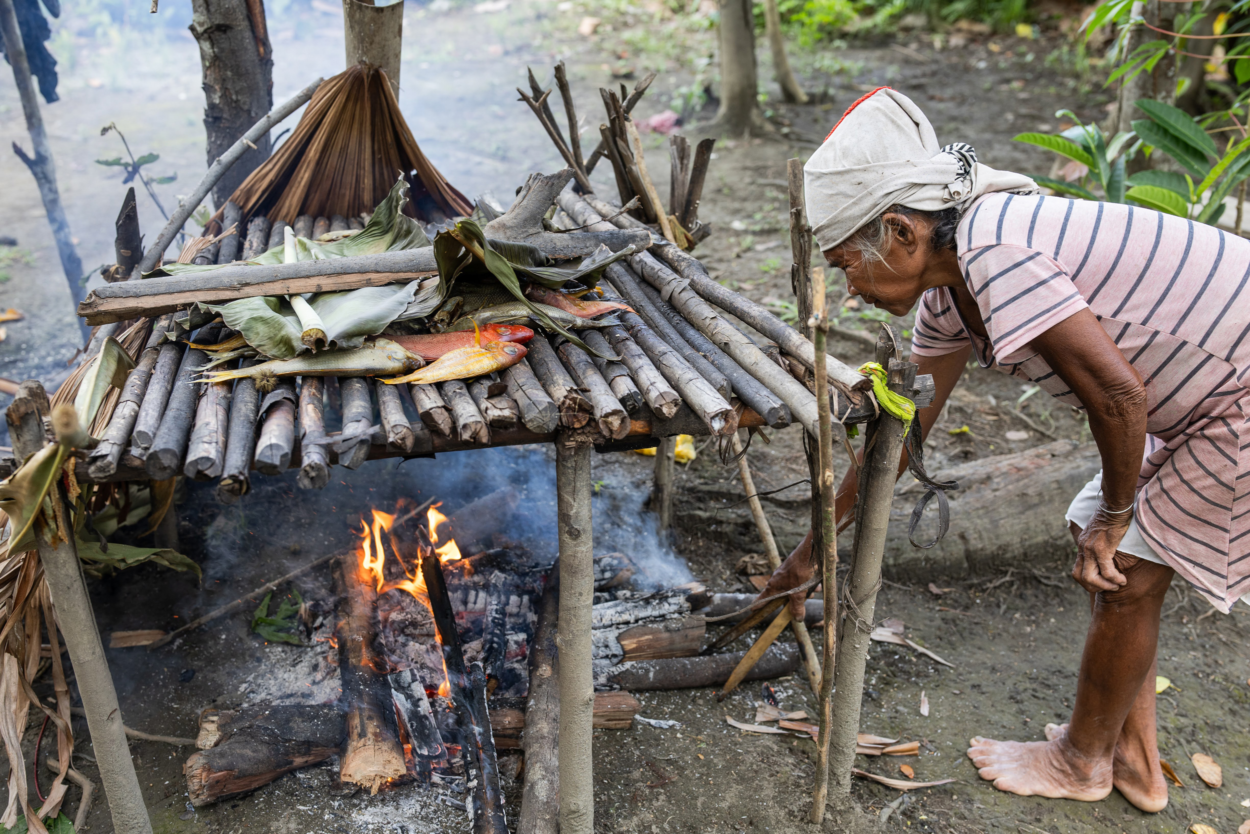 A woman from the O'Hongana Manyawa tribe smokes fish in a remote Indigenous village in a Halmahera forest on Aug. 18, 2024.