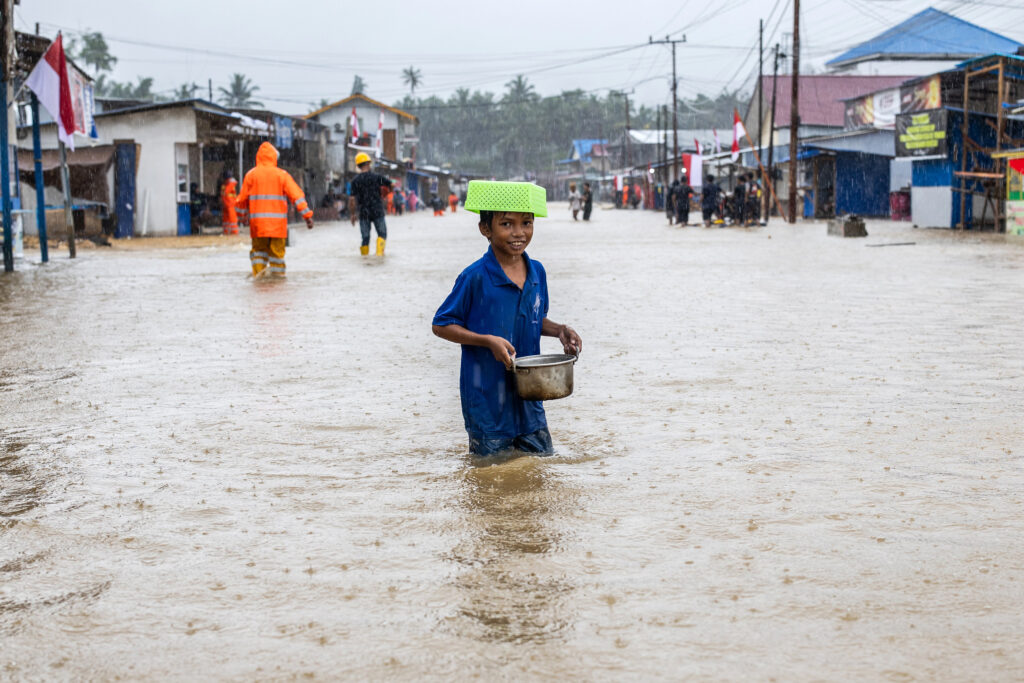 A boy carries food as he tries to wade through flood waters in the Lukulamo village of Central Halmahera on Aug. 13, 2024.