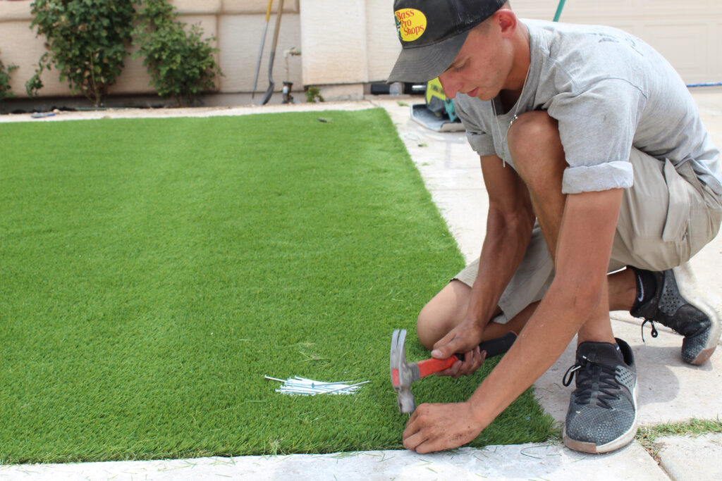 Clinton Meagher nails artificial turf into the ground at a Henderson, Nevada home on June 15, 2021. Aggressive water conservation measures have helped the Las Vegas area bring its water use down while adding population. Credit: Luke Runyon/KUNC