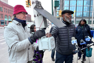 Mychal Johnson (center), co-founder of South Bronx Unite, speaks about one of the air monitors his group has installed around the New York neighborhood to measure pollution. Credit: Nicholas Kusnetz/Inside Climate News