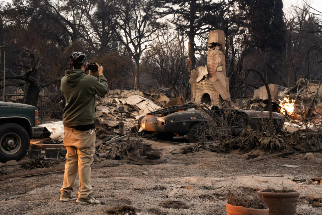 Jean-Paul Vercher photographs the damage at his friend's childhood home in Altadena. Credit: Jireh Deng/Inside Climate  News 