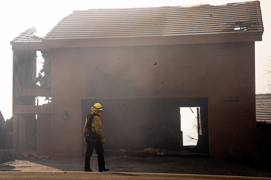 A firefighter inspects the damage at a gutted building on the Pacific Coast Highway. Credit: Jireh Deng/Inside Climate News 