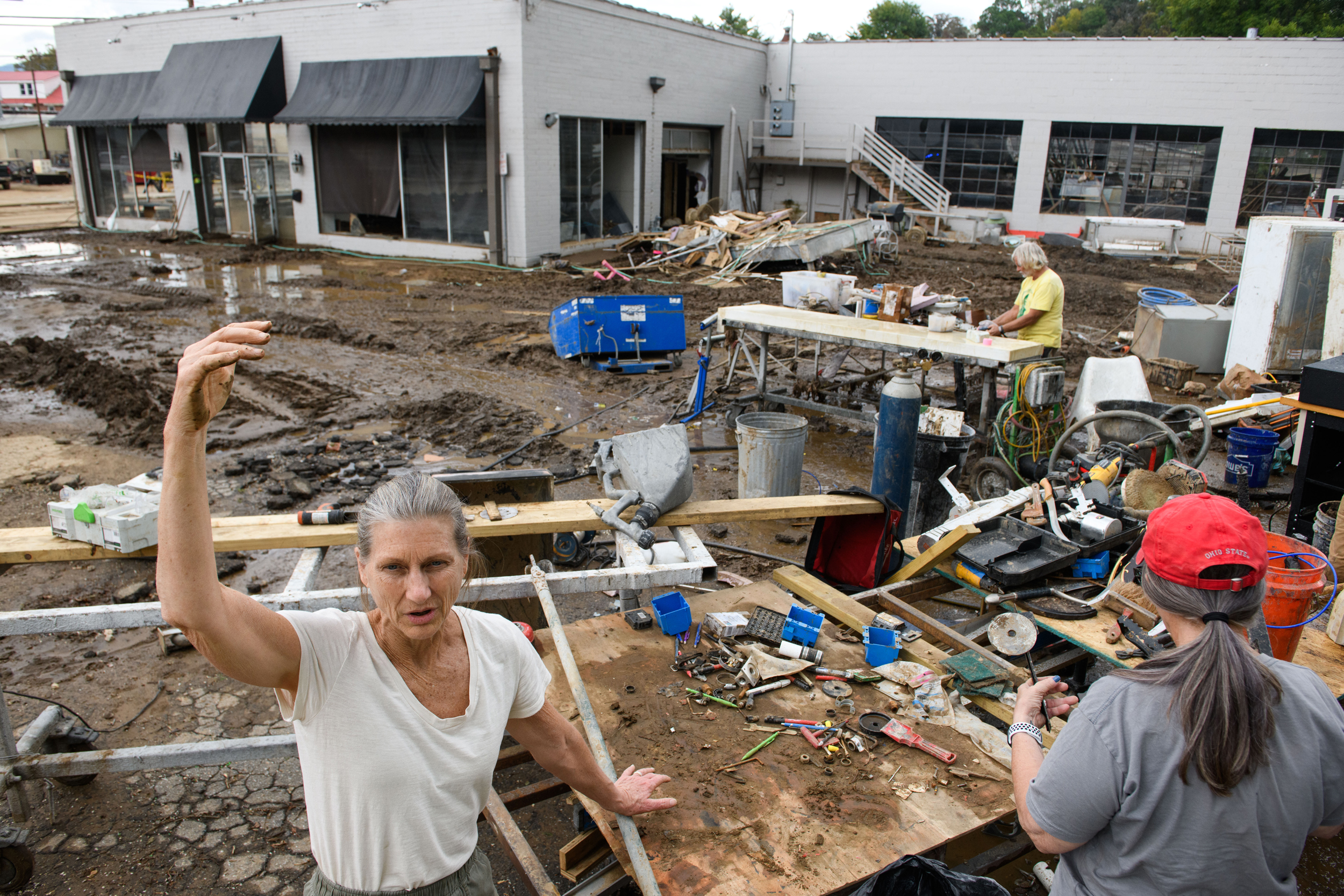 Julie Lawson (left) describes the water level of flooding that damaged her son's shop as Hurricane Helene hit Canton, N.C. in October 2024. Credit: Melissa Sue Gerrits/Getty Images