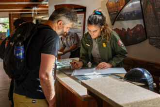 Ranger Emily Gamboa helps a visitor at the information desk at Zion National Park in Utah. Credit: NPS/Abi Farish