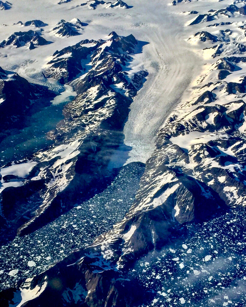 A southern Greenland glacier retreats back into a fjord, its surface scored with crevasses that can speed water flow and ice break-up. Credit: Bob Berwyn/Inside Climate News