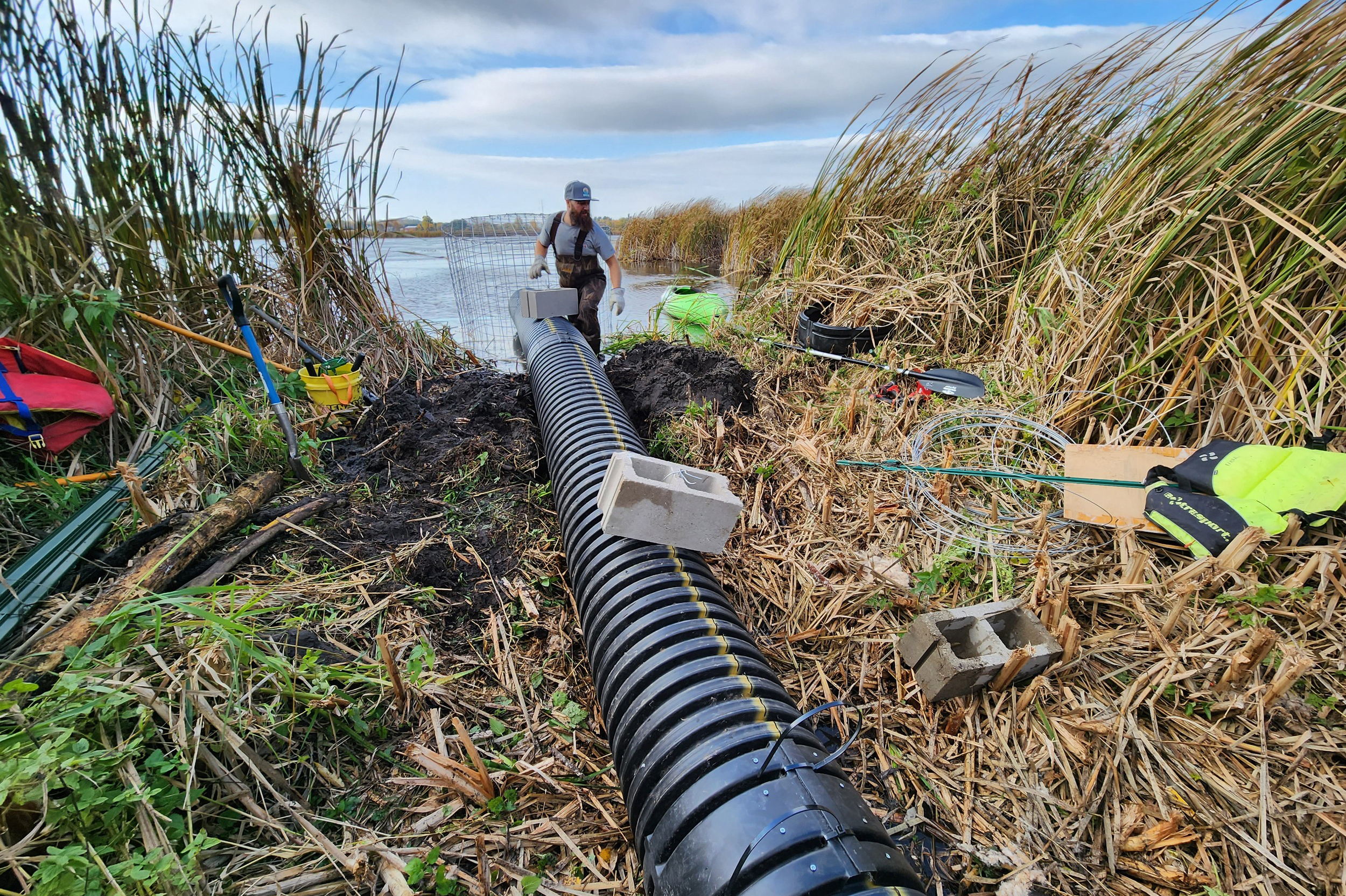 Dan Fuhs, co-owner of Native Range Ecological, installs a pond leveler in October 2023, near the village of Rio, Wis. Credit: Courtesy of Clay Frazer