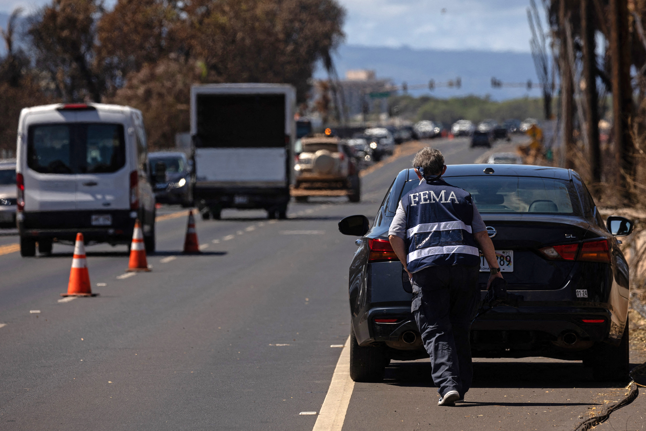A Federal Emergency Management Agency agent works with a search and recovery team to check charred buildings and cars in the aftermath of the Maui wildfires in Lahaina, Hawaii, on Aug. 18, 2023. Credit: Yuki Iwamura/AFP via Getty Images