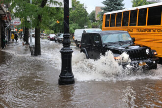 Cars drive along a flooded street on September 29, 2023, in the Brooklyn borough of New York City as remnants of Tropical Storm Ophelia reaches the Northeast. Credit: Michael M. Santiago/Getty Images