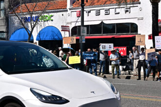 People participate in a protest against Elon Musk outside a Tesla dealership on March 8 in Pasadena, Calif. Credit: Frederic J. Brown/AFP via Getty Images