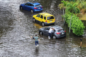 People check on a car stuck in a flooded street on June 13, 2024, in Hallandale Beach, Fla., a community that was marked as disadvantaged by the Climate and Economic Justice Screening Tool. Credit: Joe Raedle/Getty Images