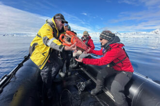Tudor Morgan, with HX Expeditions, passes a recording device called a SoundTrap to Heidi Ahonen, a bioacoustician who has launched the first long-term project to monitor whales in the Gerlache Strait using passive acoustic monitoring. Credit: Teresa Tomassoni/Inside Climate News